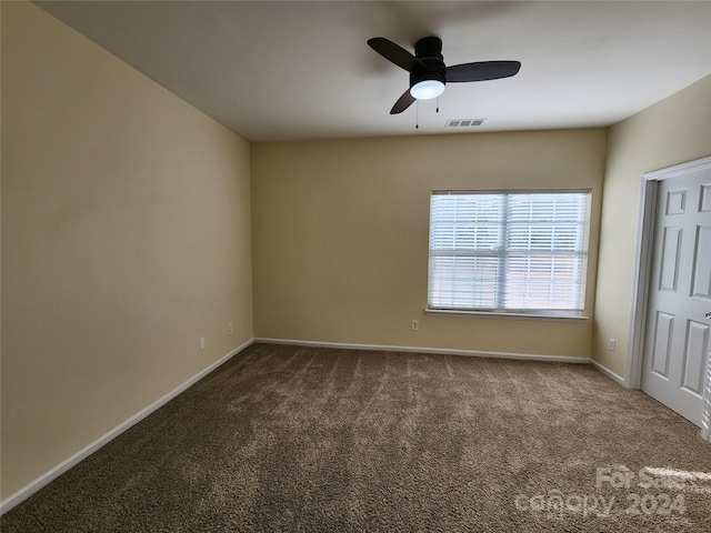 spare room featuring dark colored carpet and ceiling fan