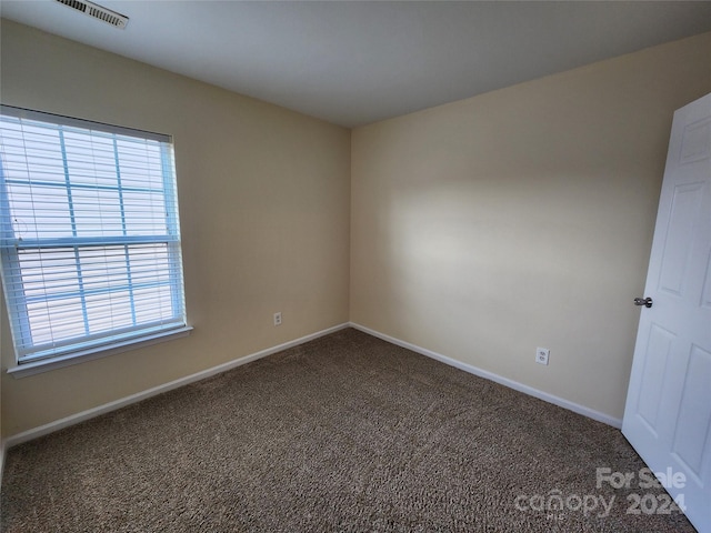 unfurnished room featuring dark colored carpet