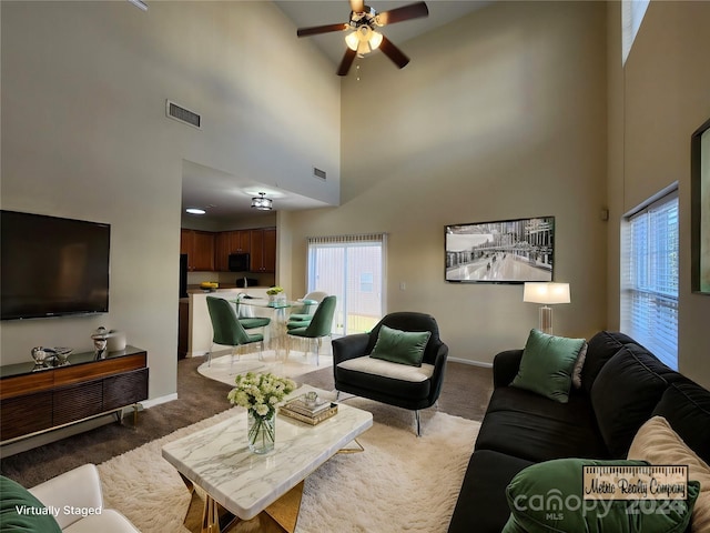 carpeted living room with a high ceiling and ceiling fan