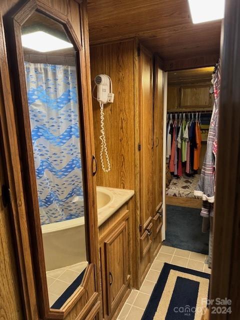 bathroom featuring vanity, tile patterned floors, wood walls, and wood ceiling