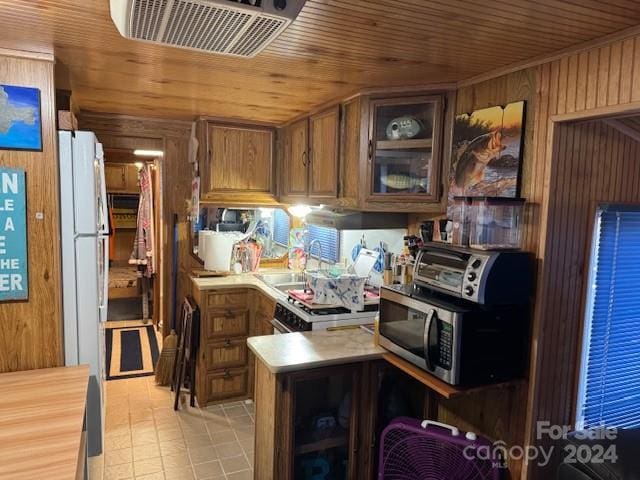 kitchen with wood ceiling, kitchen peninsula, wood walls, and stainless steel appliances