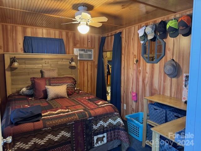 bedroom featuring a wall unit AC, wood ceiling, ceiling fan, and wood walls