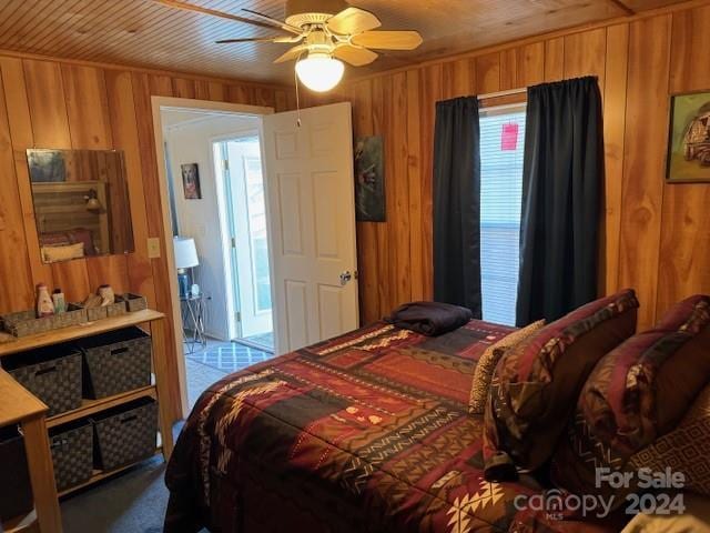 bedroom with ceiling fan, wooden ceiling, and wood walls