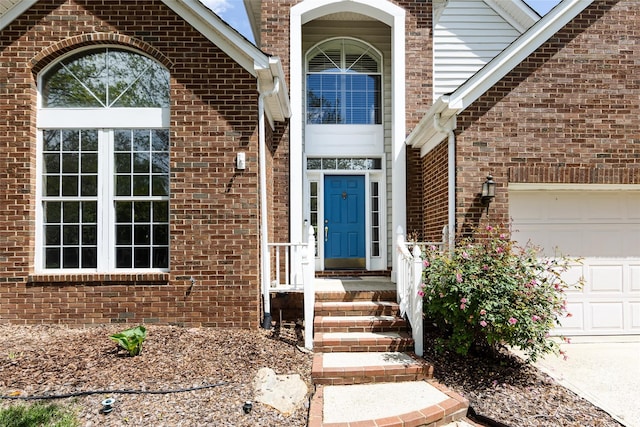 entrance to property featuring an attached garage and brick siding