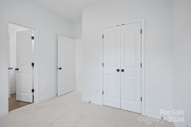 unfurnished bedroom with a closet and light colored carpet