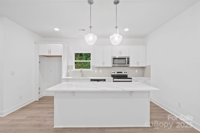 kitchen featuring pendant lighting, sink, a kitchen island, and appliances with stainless steel finishes