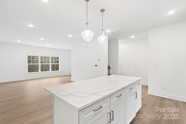 kitchen featuring white cabinetry, hanging light fixtures, a center island, light stone countertops, and light hardwood / wood-style flooring