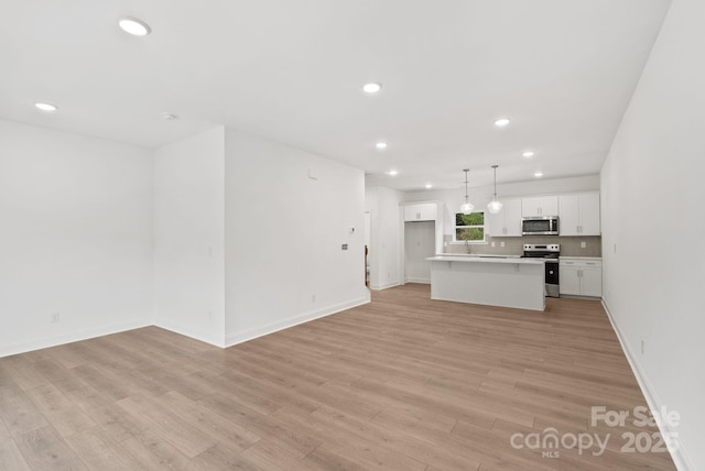 kitchen featuring a center island, hanging light fixtures, appliances with stainless steel finishes, light hardwood / wood-style floors, and white cabinets