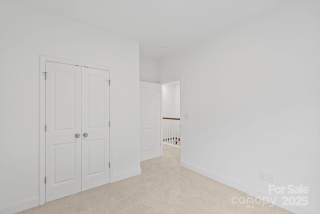 unfurnished bedroom featuring light colored carpet and a closet