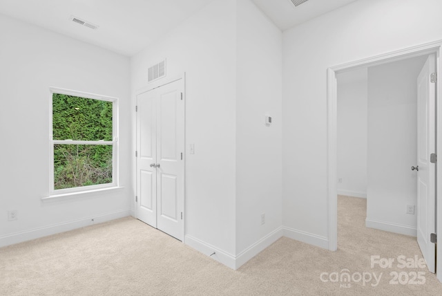 unfurnished bedroom featuring a closet and light carpet