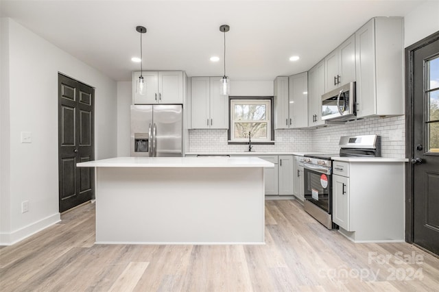 kitchen with decorative light fixtures, stainless steel appliances, a kitchen island, and a healthy amount of sunlight