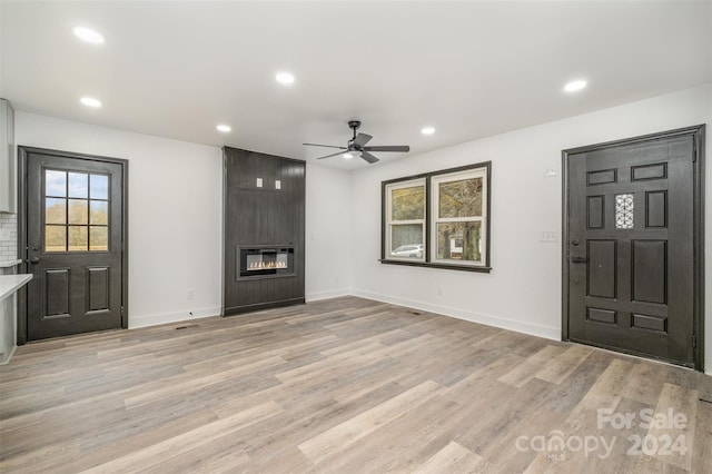 entrance foyer with a large fireplace, light hardwood / wood-style floors, and ceiling fan