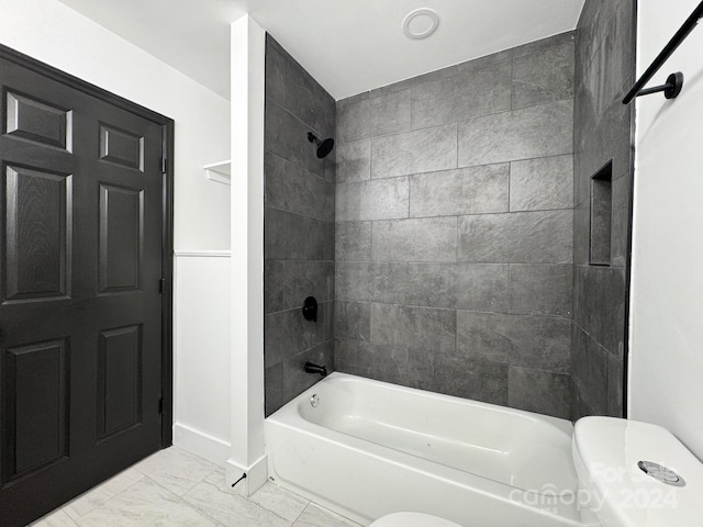 bathroom featuring toilet and tiled shower / bath