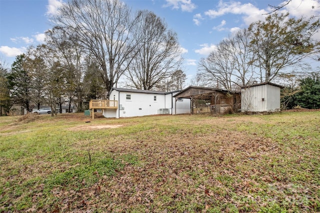 view of yard with a carport, a deck, and a storage shed