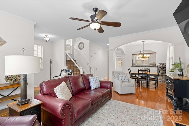 living room with hardwood / wood-style flooring, crown molding, and ceiling fan with notable chandelier