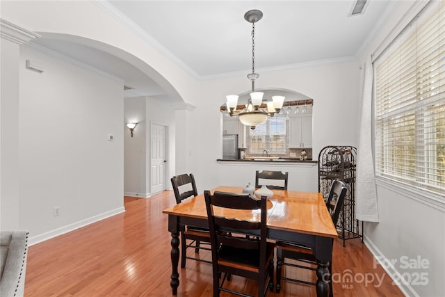 dining area with an inviting chandelier, light hardwood / wood-style flooring, and ornamental molding