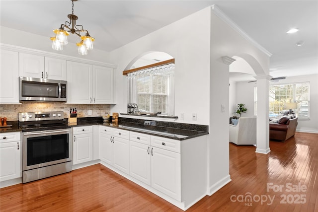 kitchen with white cabinetry, appliances with stainless steel finishes, light hardwood / wood-style flooring, and backsplash