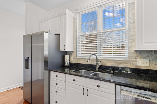 kitchen with sink, white cabinetry, dark stone countertops, stainless steel appliances, and decorative backsplash