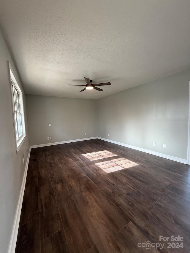 spare room with ceiling fan, dark wood-type flooring, and a textured ceiling