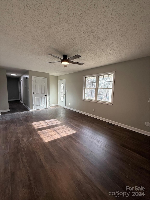 unfurnished living room featuring ceiling fan, dark wood-type flooring, and a textured ceiling