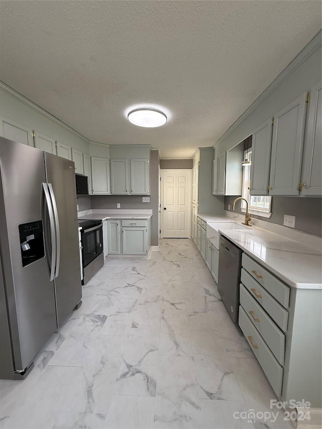 kitchen featuring appliances with stainless steel finishes, a textured ceiling, gray cabinets, and sink