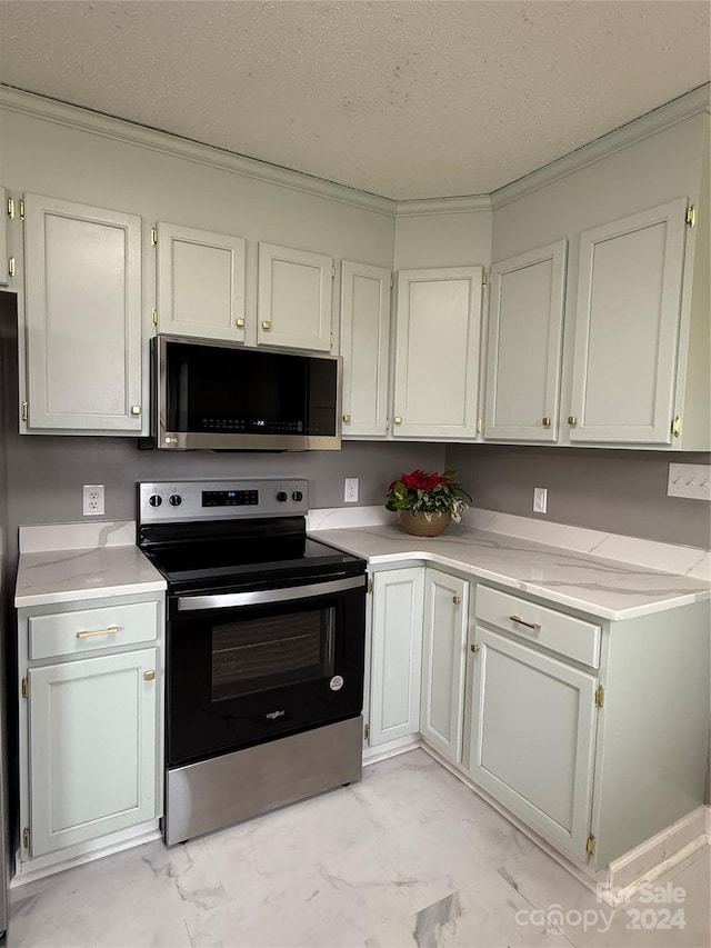 kitchen with appliances with stainless steel finishes, a textured ceiling, white cabinetry, and ornamental molding