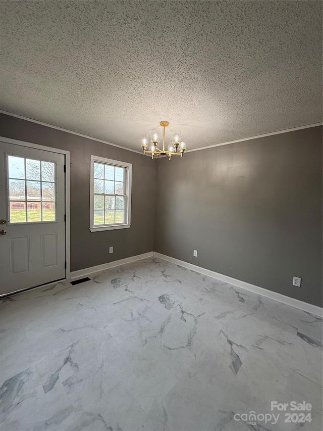 unfurnished dining area with a chandelier, a textured ceiling, and ornamental molding