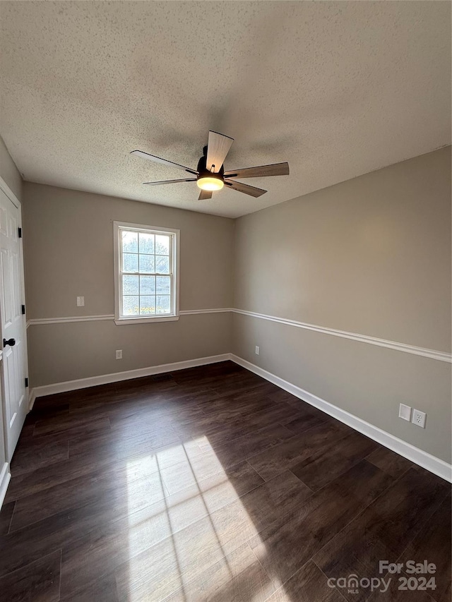 empty room featuring a textured ceiling, ceiling fan, and dark wood-type flooring