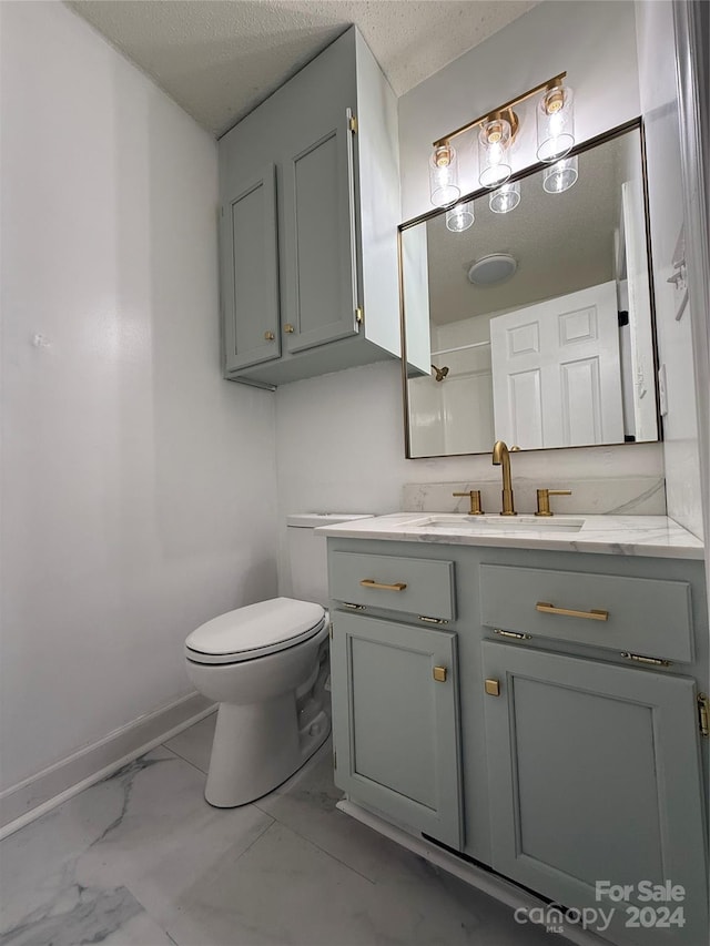 bathroom featuring a textured ceiling, vanity, and toilet