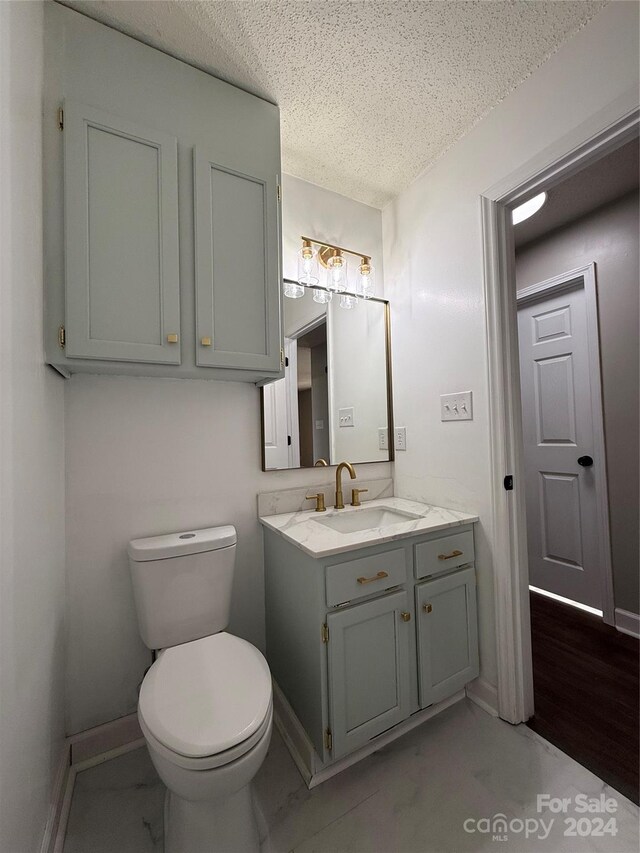 bathroom featuring a textured ceiling, vanity, and toilet