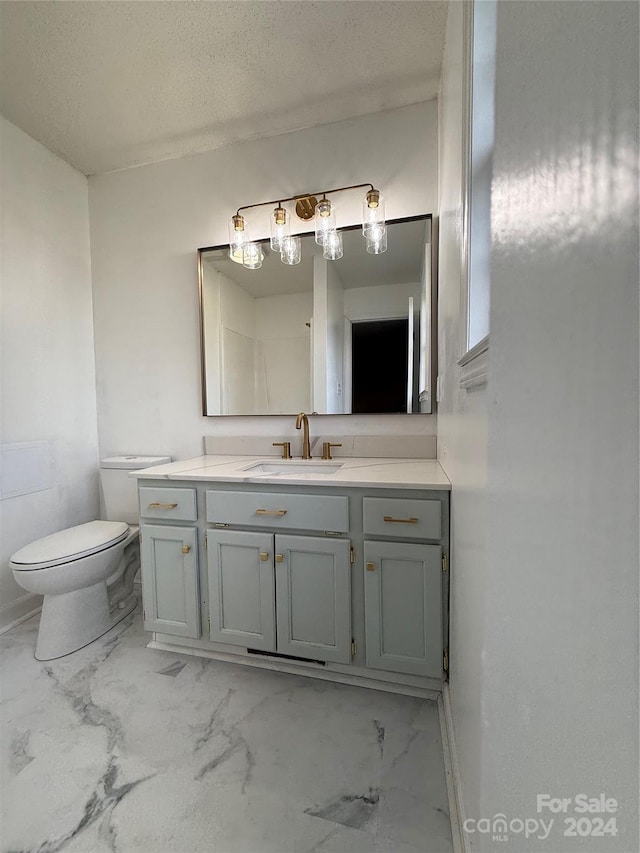 bathroom with vanity, a textured ceiling, and toilet