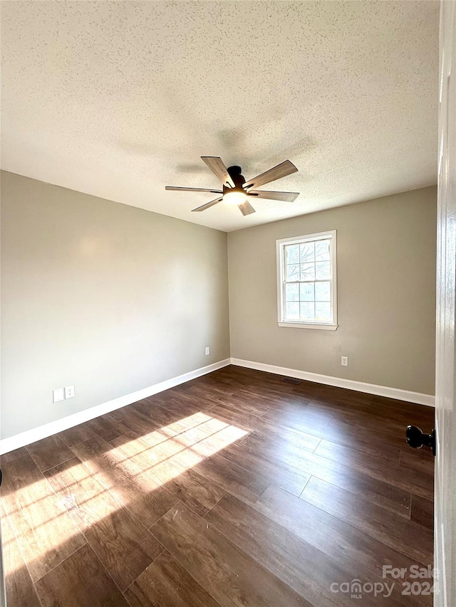 unfurnished room with ceiling fan, dark wood-type flooring, and a textured ceiling