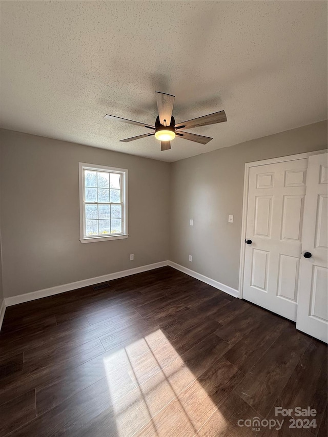 spare room featuring ceiling fan, dark hardwood / wood-style flooring, and a textured ceiling