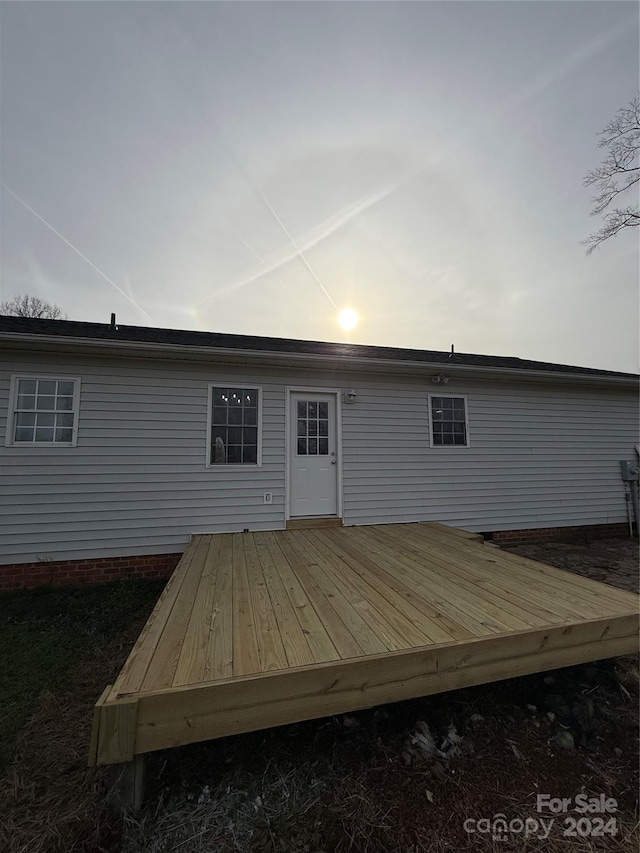 back house at dusk with a wooden deck