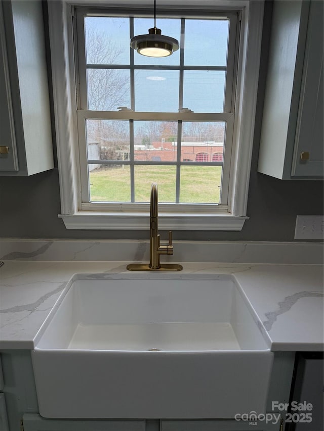 details with gray cabinets, sink, and light stone counters