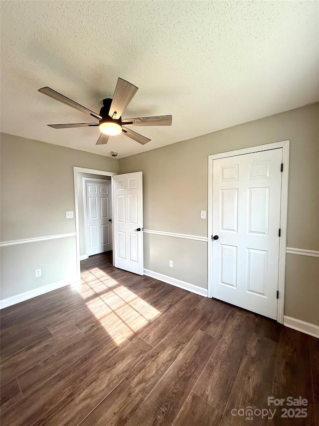 unfurnished bedroom with ceiling fan, dark wood-type flooring, and a textured ceiling