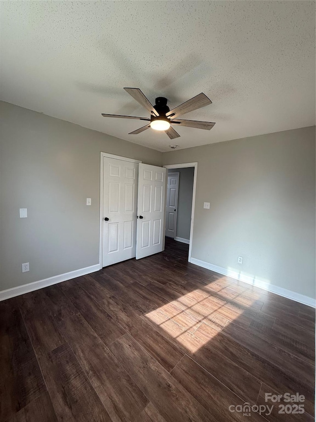 unfurnished bedroom featuring ceiling fan, dark wood-type flooring, and a textured ceiling