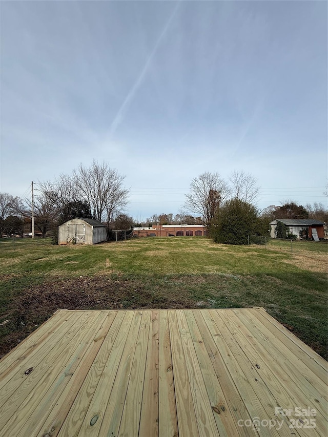 wooden terrace featuring a storage shed and a lawn