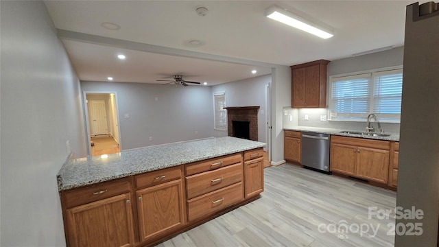 kitchen with sink, light stone counters, a brick fireplace, light hardwood / wood-style flooring, and dishwasher