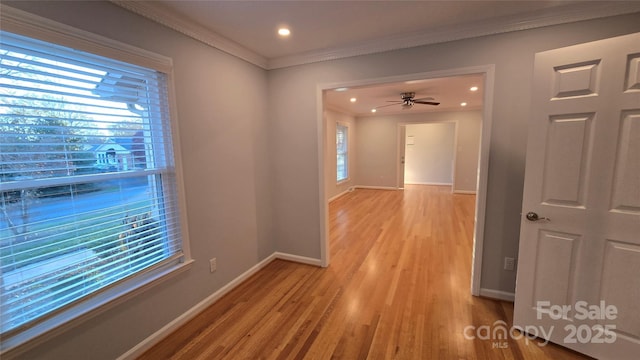 hall with light wood-style floors, plenty of natural light, baseboards, and crown molding