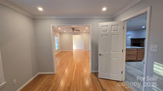 hallway featuring light wood-type flooring, crown molding, baseboards, and recessed lighting