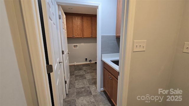 laundry room with cabinet space, baseboards, hookup for a washing machine, and stone finish floor
