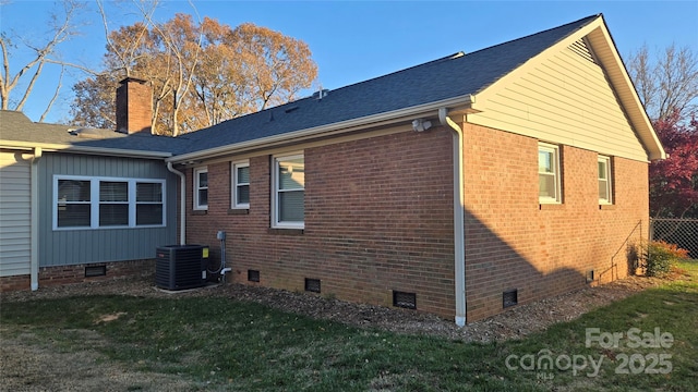 view of side of property featuring central AC unit, brick siding, crawl space, a lawn, and a chimney