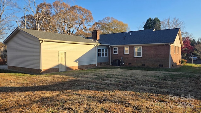 rear view of house featuring cooling unit, brick siding, crawl space, a lawn, and a chimney