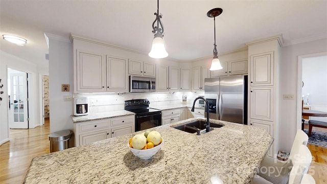 kitchen with a sink, hanging light fixtures, ornamental molding, appliances with stainless steel finishes, and light stone countertops