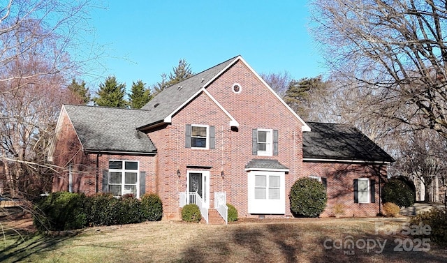 view of front of property featuring a front yard, brick siding, and roof with shingles