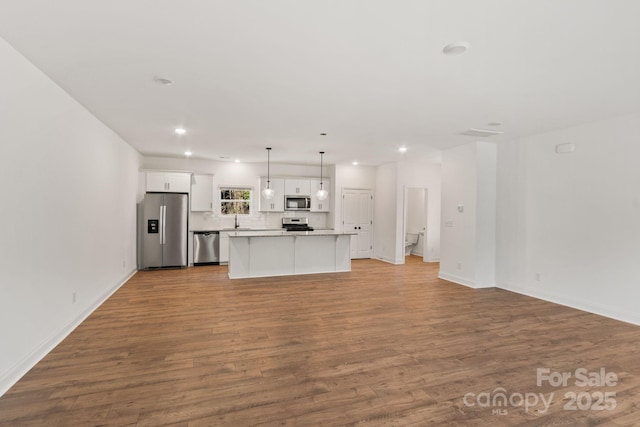 kitchen featuring a kitchen island, decorative light fixtures, white cabinetry, stainless steel appliances, and light wood-type flooring