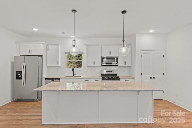 kitchen with appliances with stainless steel finishes, sink, white cabinets, and light stone counters