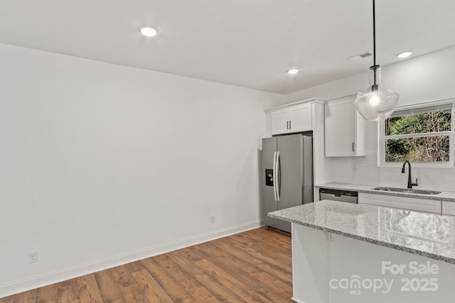 kitchen featuring sink, light stone counters, hanging light fixtures, stainless steel appliances, and white cabinets