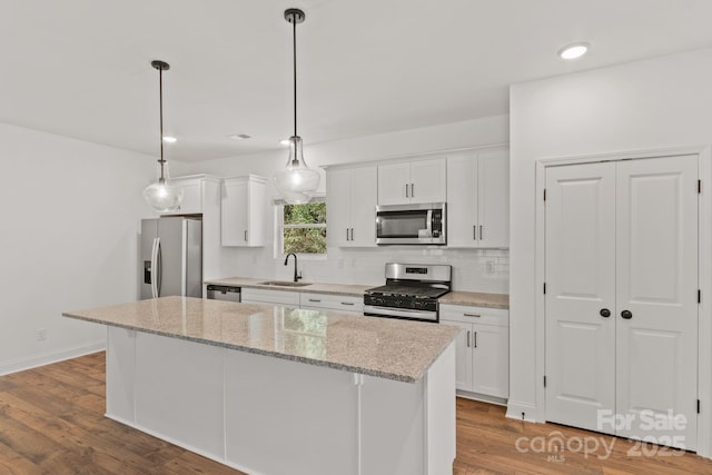 kitchen featuring pendant lighting, sink, white cabinets, a center island, and stainless steel appliances